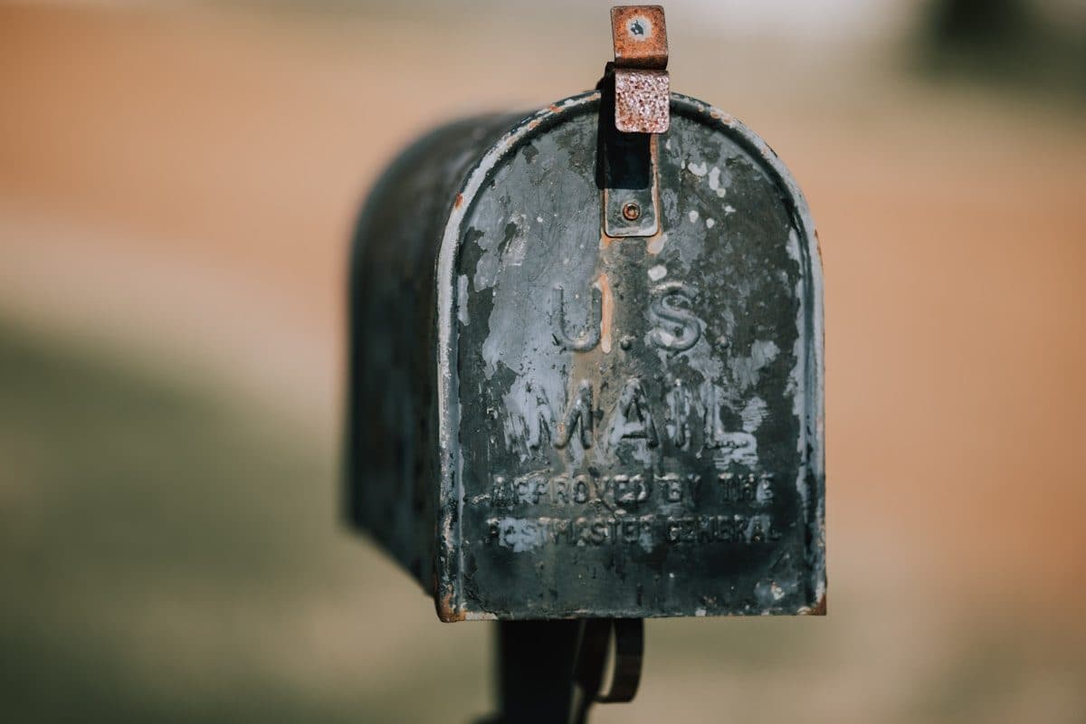 Weathered US Mail mailbox photographed close up against a blurred field